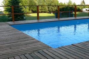 een zwembad met een houten terras en blauw water bij Dworek Karpińskich in Sandomierz