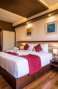 a bedroom with a large white bed with red pillows at KPM TRIPENTA HOTEL in Kozhikode