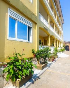 um edifício amarelo com vasos de plantas em frente em Karibu BB Suites em Entebbe