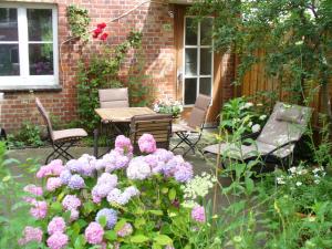 a garden with pink flowers and a table and chairs at Ferienwohnung Riedner in Lüneburg