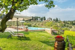 een tuin met een zwembad en een stoel en een parasol bij Borgo Divino in Montespertoli