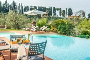 een zwembad met stoelen en een tafel met eten en een parasol bij Borgo Divino in Montespertoli