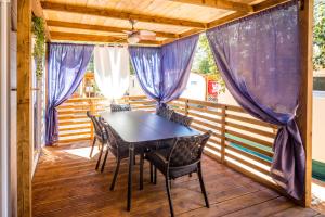 een afgeschermde veranda met een tafel en stoelen bij Mobile Home HappyNest in Biograd na Moru