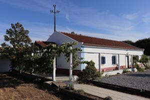 uma pequena igreja branca com uma cruz no telhado em Monte do Parral em Santiago do Cacém