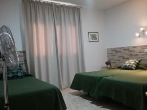 - une chambre avec 2 lits verts et une fenêtre dans l'établissement Hostal Residencia Cardona, à Arrecife