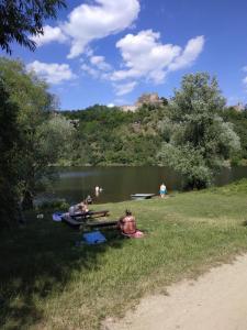 un gruppo di persone seduti a un tavolo da picnic vicino a un lago di Pod hradem Cornštejn a Oslnovice