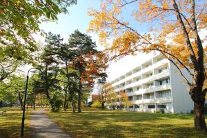 a building in a park with trees and a sidewalk at College Garden Hotel in Bad Vöslau