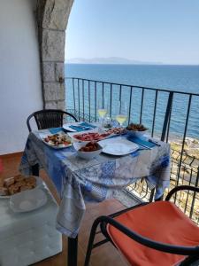 uma mesa com comida numa varanda com o oceano em Albatros House em L'Escala