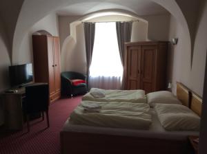 a hotel room with a bed and a window at Hotel U Zlateho Andela in Pardubice