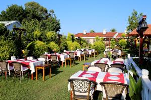 een rij tafels en stoelen met rode en witte servetten bij Nerissa Hotel in Cıralı