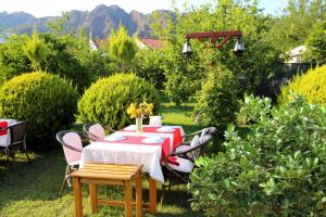 een tafel in een tuin met een rode en witte tafelkleed bij Nerissa Hotel in Cıralı