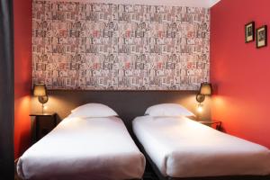 two beds in a room with a red wall at Hôtel Bristol Reims in Reims