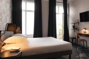 a hotel room with a bed and a window at Hôtel Bristol Reims in Reims