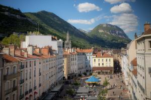 vistas a una ciudad con montañas en el fondo en Hôtel de l'Europe Grenoble hyper-centre, en Grenoble