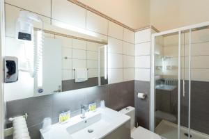 y baño blanco con lavabo y ducha. en Hôtel de l'Europe Grenoble hyper-centre, en Grenoble