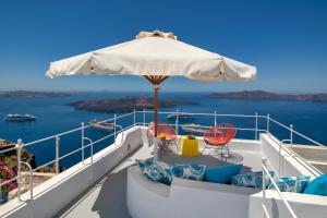 een balkon met een parasol en stoelen op een boot bij Barocco Bello Villa in Fira