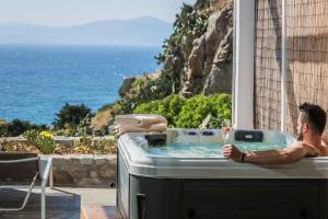 een man in een bad met uitzicht op de oceaan bij KLIDON Dreamy Living Suites in Mykonos-stad