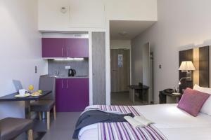 1 dormitorio con 1 cama y cocina con armarios morados en Odalys City Dijon Les Cordeliers, en Dijon