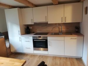 eine Küche mit weißen Schränken und einem Waschbecken in der Unterkunft Ferienwohnung Klammhof in Zell am Ziller