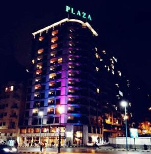 un edificio alto con luces moradas en él por la noche en Plaza Hotel Alexandria en Alexandría