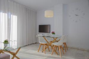 uma sala de jantar com mesa e cadeiras e um relógio em Domus Apartamentos Granada con parking gratuito en pleno centro em Granada