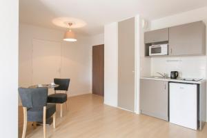 een keuken en eetkamer met een tafel en stoelen bij Zenao Appart'hôtels Troyes in Troyes