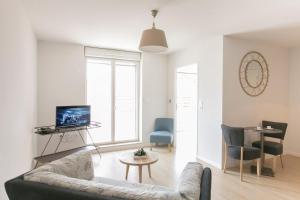 een woonkamer met een bank en een tv bij Zenao Appart'hôtels Troyes in Troyes