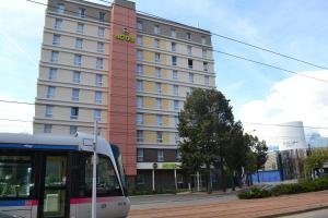 un tren delante de un edificio alto en B&B HOTEL Grenoble Centre Alpexpo, en Grenoble