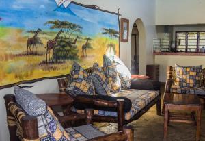 un salon avec un canapé et une peinture de girafes dans l'établissement Oasis Diani Beach Villas, à Diani Beach