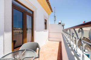 einen Balkon mit einem Tisch und Stühlen auf einem Gebäude in der Unterkunft Residencial Mares in Tavira