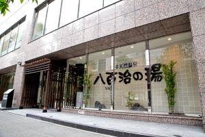 ein Geschäft vor einem Gebäude mit Schreiben am Fenster in der Unterkunft Natural Hot Spring Yaoji Hakata Hotel in Fukuoka