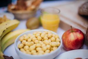 uma mesa com uma tigela de comida, uma maçã e laranjas em DC Hotel Charleroi Airport em Charleroi