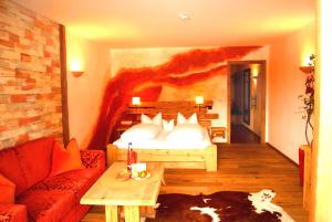 une chambre d'hôtel avec un lit et un canapé dans l'établissement Feuriger Tatzlwurm, à Oberaudorf