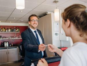 um homem dando a uma mulher um pedaço de papel em DC Hotel Charleroi Airport em Charleroi