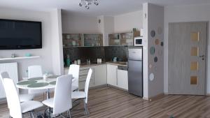 Il comprend une cuisine et une salle à manger avec une table et des chaises blanches. dans l'établissement Angel Apartament, à Władysławowo