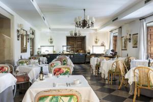 un restaurant avec des tables et des chaises blanches et un lustre dans l'établissement Parador de Pontevedra, à Pontevedra