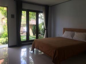 1 dormitorio con cama y ventana grande en Bali Full Moon Guest House, en Canggu