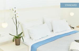 uma cama branca com almofadas brancas e um vaso de plantas em Inspira Boutique Hotel Thassos - Adults Only em Prinos