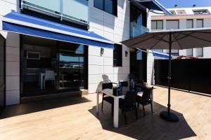 - une table avec des chaises et un parasol sur la terrasse dans l'établissement Apartamentos Playa De Los Barcos, à Isla