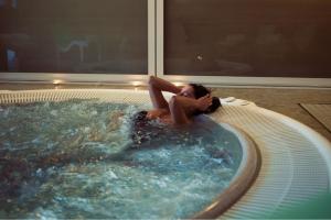 a woman laying in a hot tub in a room at Grand Hotel Sestriere in Sestriere