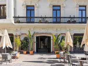 um edifício com mesas, cadeiras e guarda-sóis em H10 Palacio Colomera em Córdoba