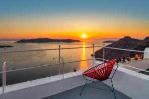 een rode stoel op een balkon met uitzicht op de zonsondergang bij Barocco Bello Villa in Fira