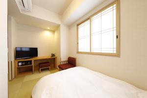 a bedroom with a bed and a tv and a window at Onyado Nono Asakusa Natural Hot Spring in Tokyo