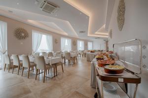 uma grande sala de jantar com mesas e cadeiras com comida em Roma Hotel em Castiglione della Pescaia