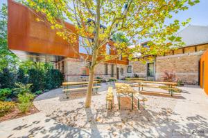 a group of benches and a tree in front of a building at Domaine de Ronchinne - Maison du Jardinier in Maillen