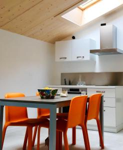 a kitchen with a table and some orange chairs at La Corte Room & Relax in Rovereto