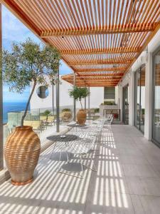 um pátio com uma mesa, cadeiras e uma árvore em Lindos Mare, Seaside Hotel em Líndos