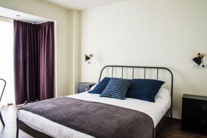 a bedroom with a bed with blue pillows and a window at Apartamentos Estela de Altamira in Santillana del Mar