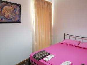 una camera con letto rosa con due telecomandi di Houses in the Village2 a Kavala