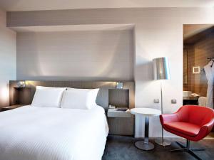 une chambre d'hôtel avec un lit et un fauteuil rouge dans l'établissement Pullman Toulouse Centre Ramblas, à Toulouse